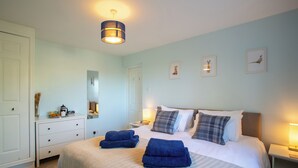 Une chambre à coucher avec un lit, des tables de chevet, une commode et un miroir.