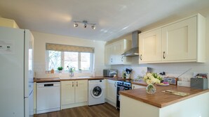 Une cuisine moderne avec des meubles blancs, un lave-vaisselle, une machine à laver et une cuisinière.