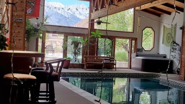 An indoor swimming pool with a wooden ceiling, a bar area, and a seating area with chairs and tables. - ***Million Dollar Views and Indoor Pool! (Lone Pine)