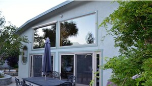 A modern house with a patio area featuring a table and chairs, large windows, and a sliding glass door. - ***Million Dollar Views and Indoor Pool! (Lone Pine)