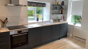 Een moderne keuken met een Bosch oven, een inbouwmagnetron en een groot raam met uitzicht op groen.
