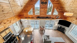 A spacious loft-style living area with a kitchen, dining area, and a large TV screen. - Deer Crossing Retreat - new home close to Saddleback (Dallas Plantation)