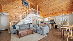 A spacious living room with a gray sectional sofa, a wooden coffee table, and a staircase leading to an upper level. - Deer Crossing Retreat - new home close to Saddleback (Dallas Plantation)