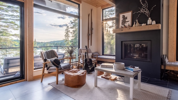Una sala de estar acogedora con un ventanal grande, una guitarra, una chimenea y una estantería.