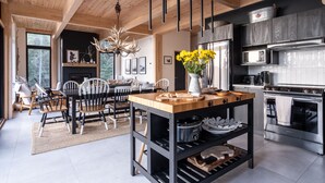Una cocina moderna con una isla central, electrodomésticos de acero inoxidable y un comedor con sillas de madera y alfombra.
