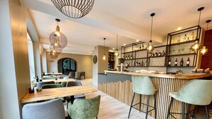 Um restaurante moderno com área de bar, mesas de madeira e banquetas.