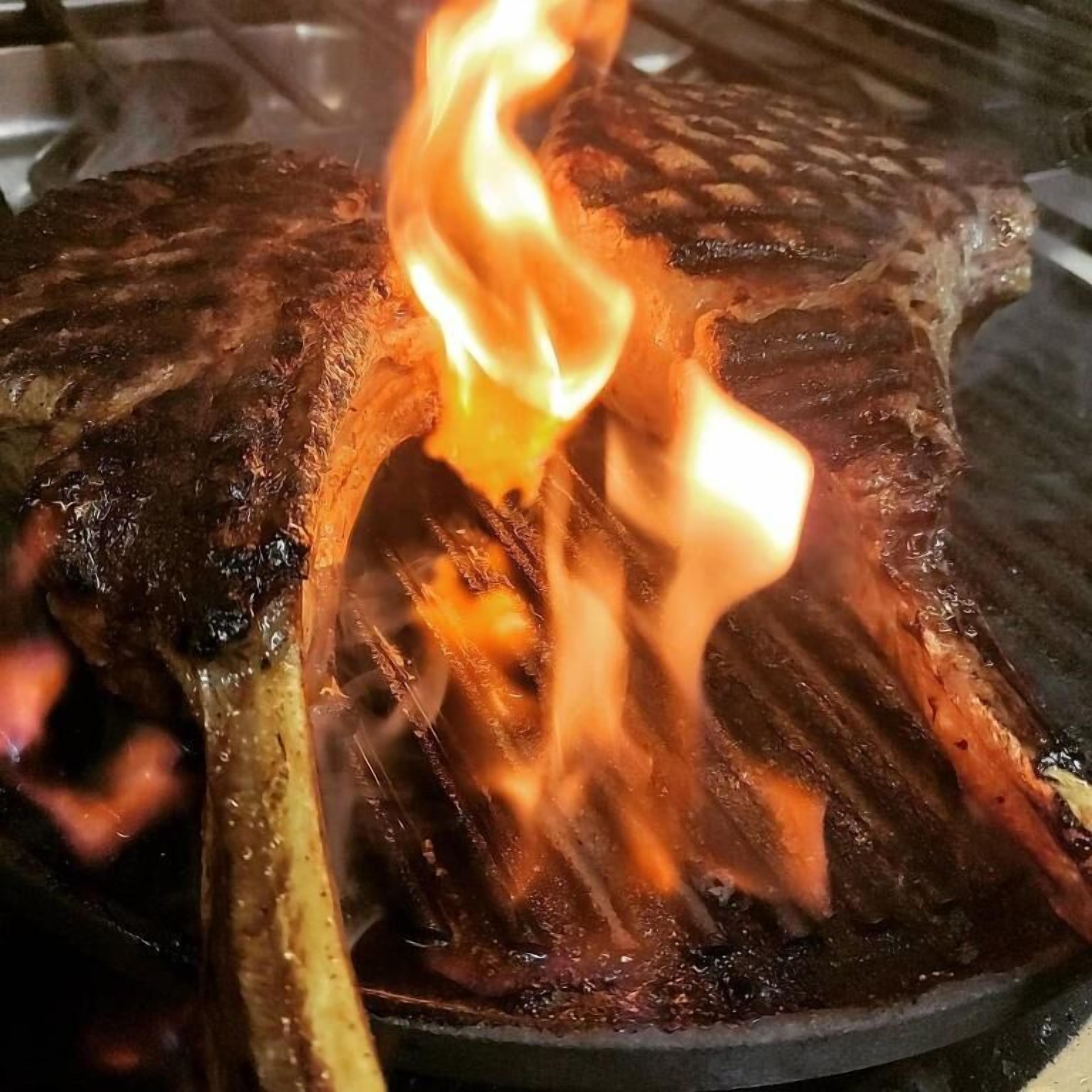 Ein Steak wird über offenem Feuer gegrillt.