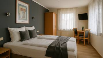 Una habitación de hotel con cama, escritorio, silla, televisión y un cuadro en la pared.
