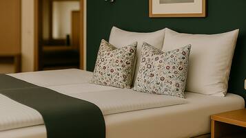 A neatly made bed with floral pillows, a green throw, and a wooden nightstand.