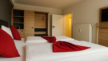 A hotel room with a bed, a wardrobe, a radiator, and a television.