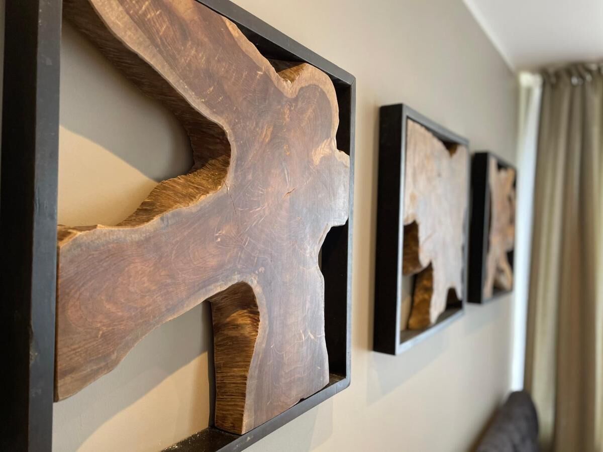 Un mur orné de trois œuvres d’art en bois.
