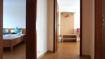 Ein Hotelzimmer mit Holzboden, einem Bett mit Kissen, einem Holzschrank und einem roten Sessel.