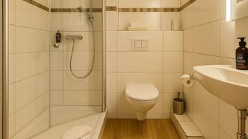 A modern bathroom with a glass shower enclosure, a toilet, and a sink.