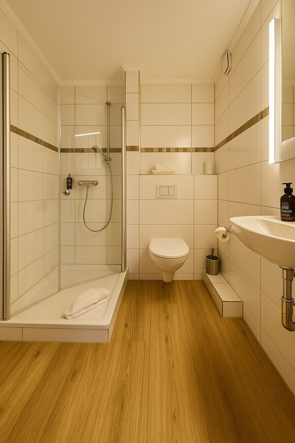 A modern bathroom with a glass shower enclosure, a toilet, and a sink. - Hotel Schultheiss 52 (Hamelin)