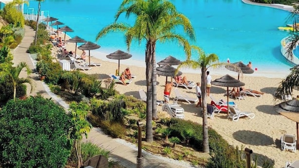 Un resort con una amplia piscina, tumbonas y palmeras.