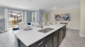 A modern kitchen with a large island, dark cabinets, and a white countertop. - Amazing Story Lake Town Home  With Pool (Kissimmee)