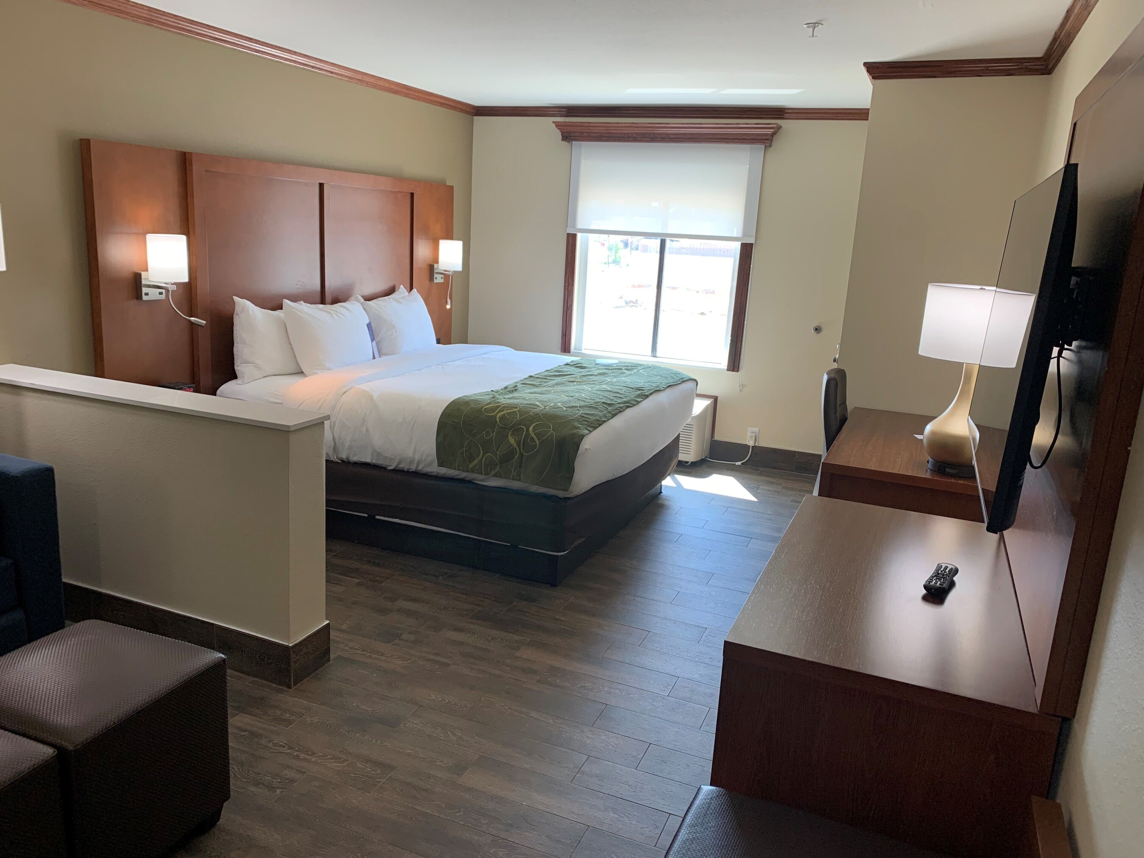 Une chambre d’hôtel équipée d’un lit, de lampes de chevet, d’une télévision, d’un bureau et d’une fenêtre avec des stores.
