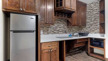 A kitchen with wooden cabinets, a stainless steel refrigerator, a tiled backsplash, and a built-in microwave.