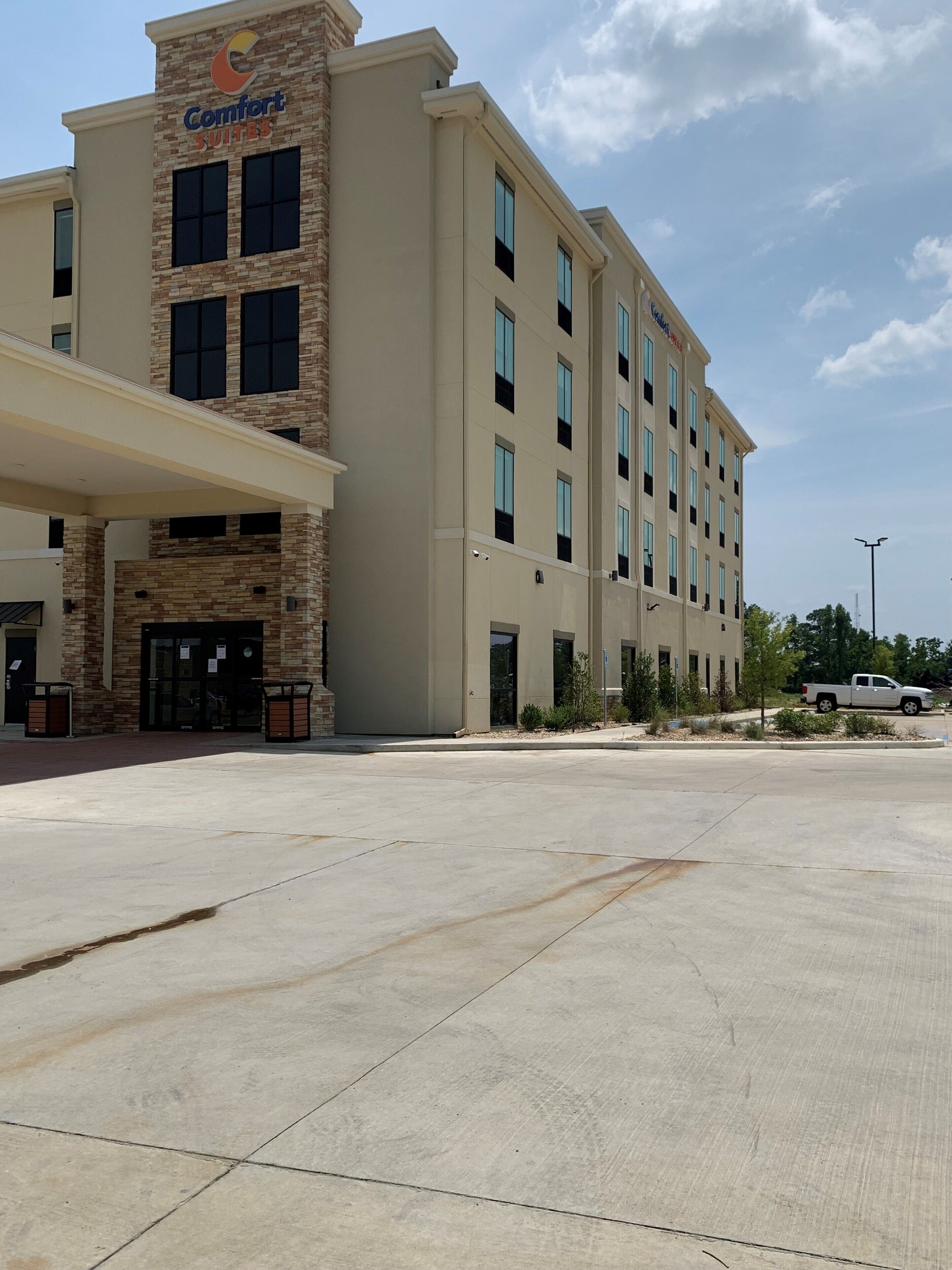 A Comfort Suites hotel with a modern facade, multiple floors, and a spacious parking lot.