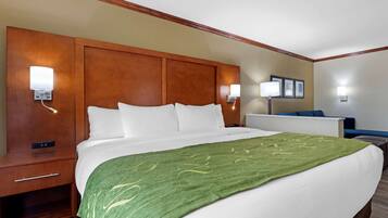 A hotel room with a large bed, wooden headboard, two bedside tables, and wall-mounted lamps.