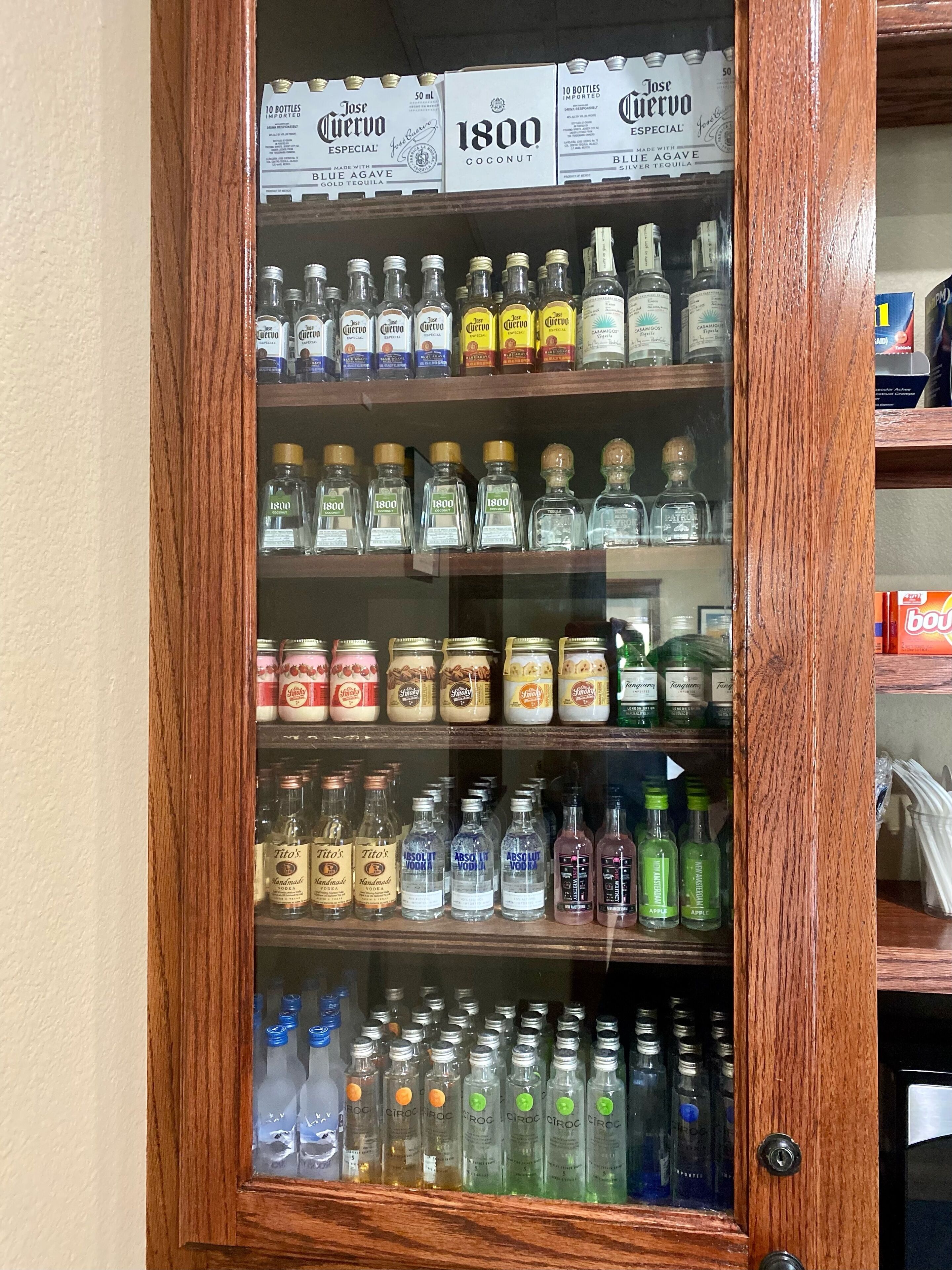 A liquor cabinet with various bottles of alcohol, including brands like Jose Cuervo and Tito's Vodka.