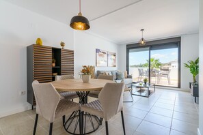 Uma sala de jantar moderna com uma mesa de madeira, cadeiras estofadas e uma luminária pendente.