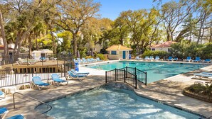 A swimming pool with lounge chairs and a small building, surrounded by trees and a fence. - Coastal stay/steps to Driftwood Beach (Jekyll Island)