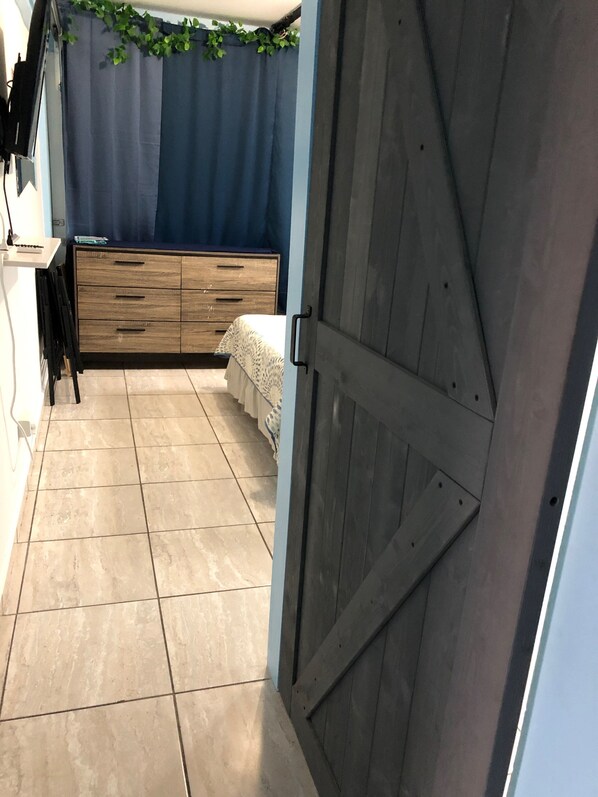 Une chambre à coucher avec un lit, une commode en bois et un rideau bleu.