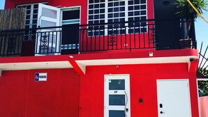 Un edificio rojo con puerta blanca, una puerta VIP y un letrero de estacionamiento.