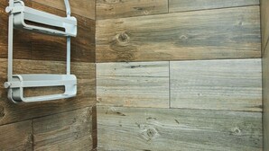 Zona de ducha con pared de madera y un perchero blanco.