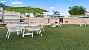 An outdoor patio area with white plastic tables and chairs, a pool, and umbrellas. - Winter Getaway Room with 2 Double Beds in Near Local Attractions (Kissimmee)