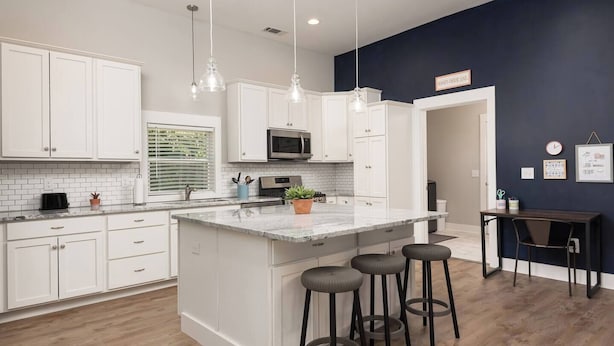 A modern kitchen with white cabinets, a marble island, and pendant lighting. - Charming Modern Farm House-5 min from Sport Center (Rock Hill)