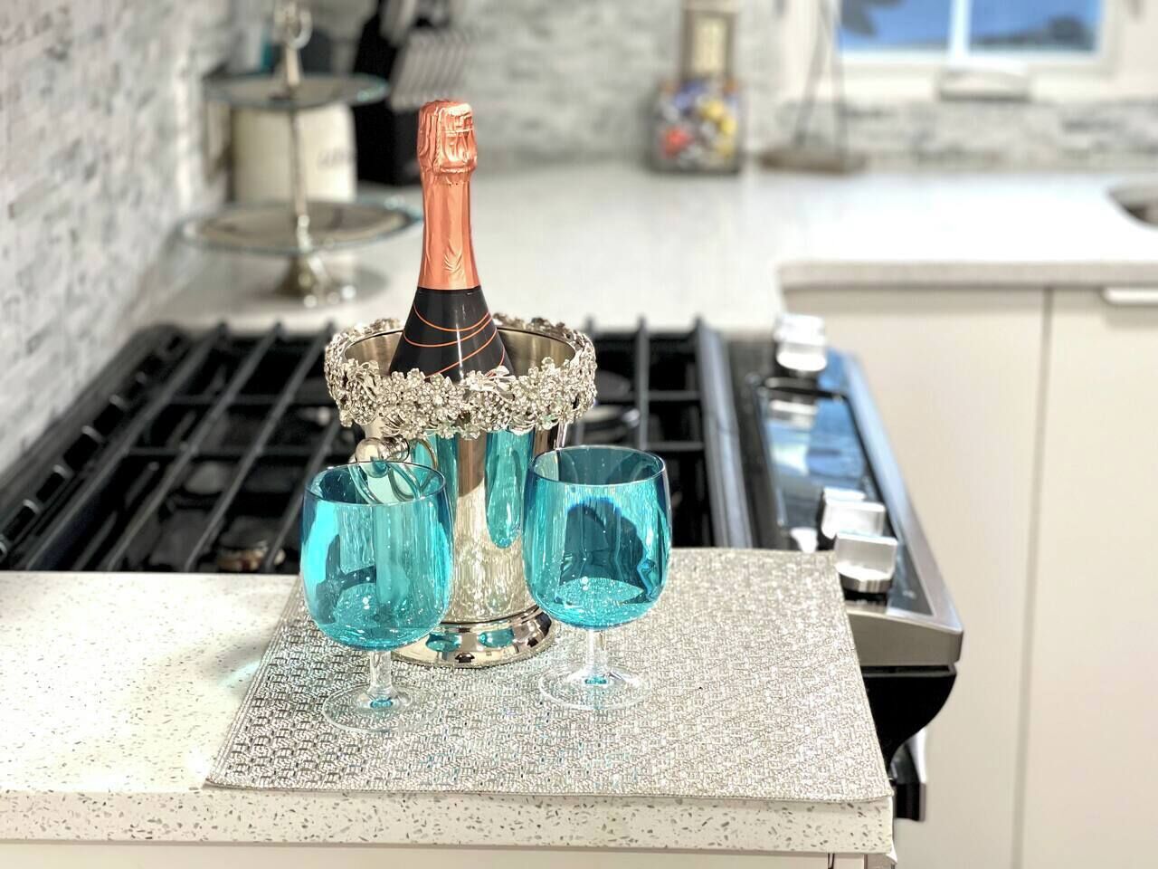 Eine Küchenarbeitsplatte mit einer Champagnerflasche, zwei Gläsern und einem dekorativen Gegenstand.