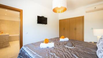 A hotel room with a bed, a television mounted on the wall, a wardrobe, and a bathroom with a shower.