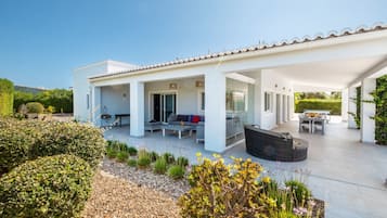 A modern house with a covered patio, outdoor seating, and a garden.