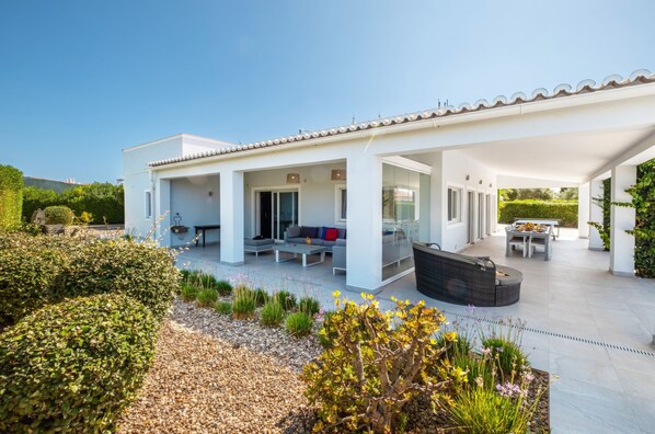 A modern house with a covered patio, outdoor seating, and a garden.