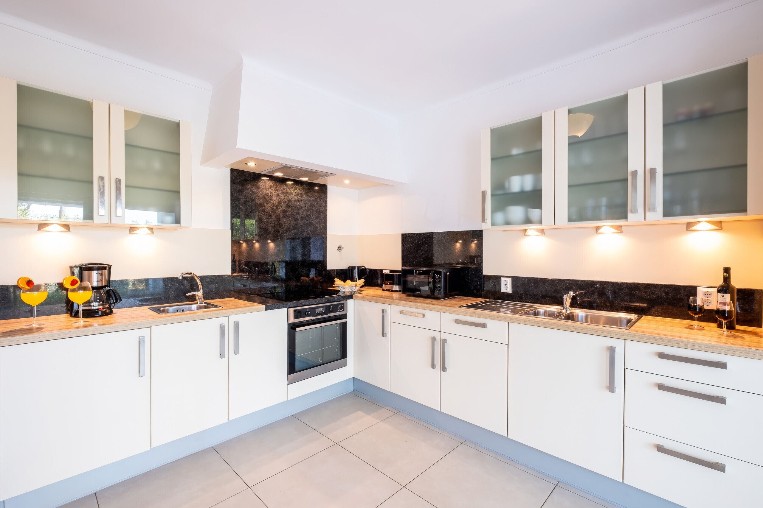 A modern kitchen with white cabinetry, black countertops, and stainless steel appliances.
