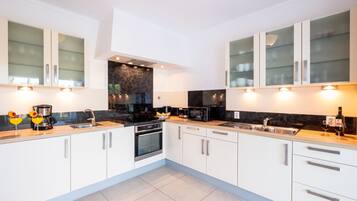 A modern kitchen with white cabinetry, black countertops, and stainless steel appliances.