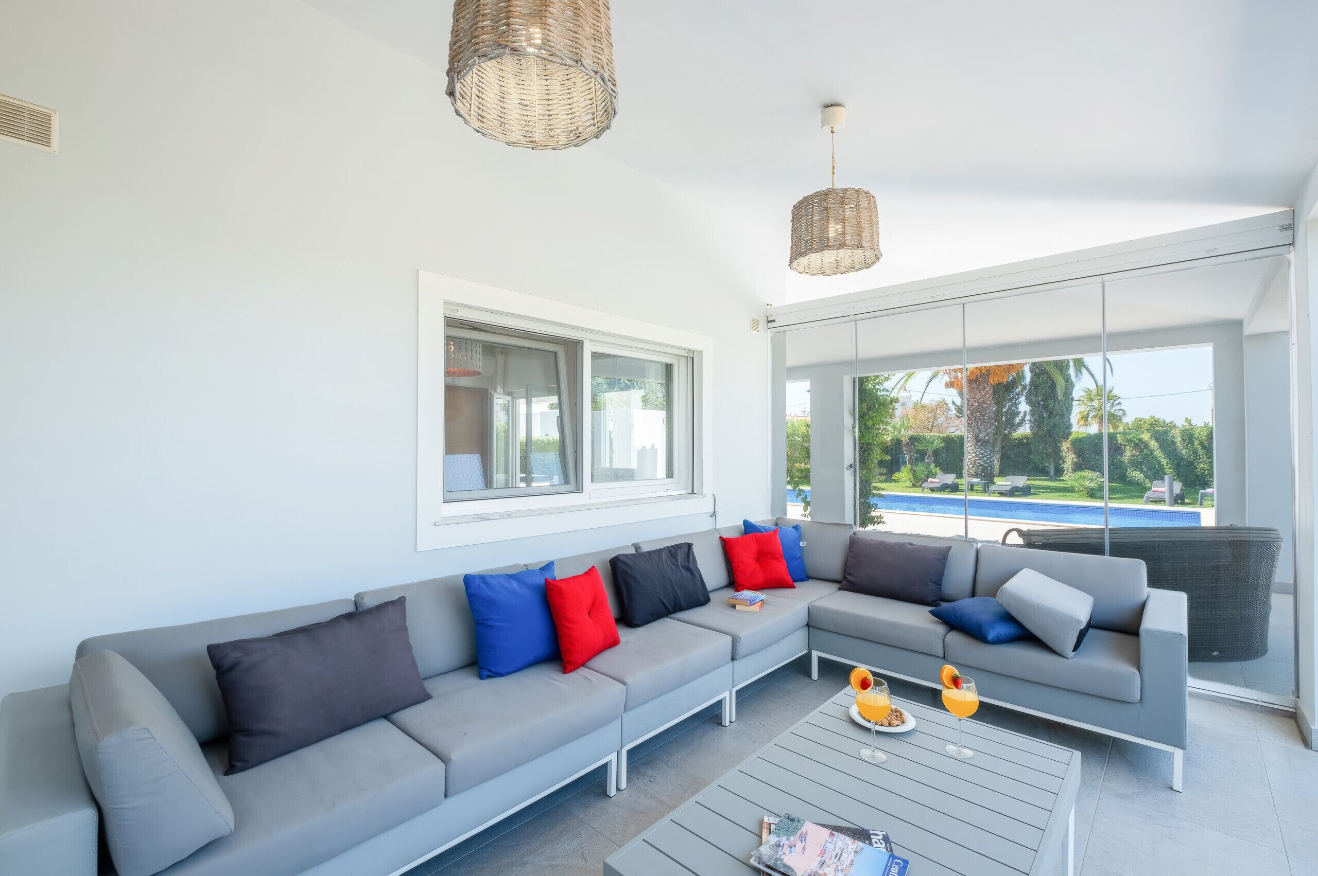 A modern living room with a grey sectional sofa, a coffee table, and a view of a swimming pool.