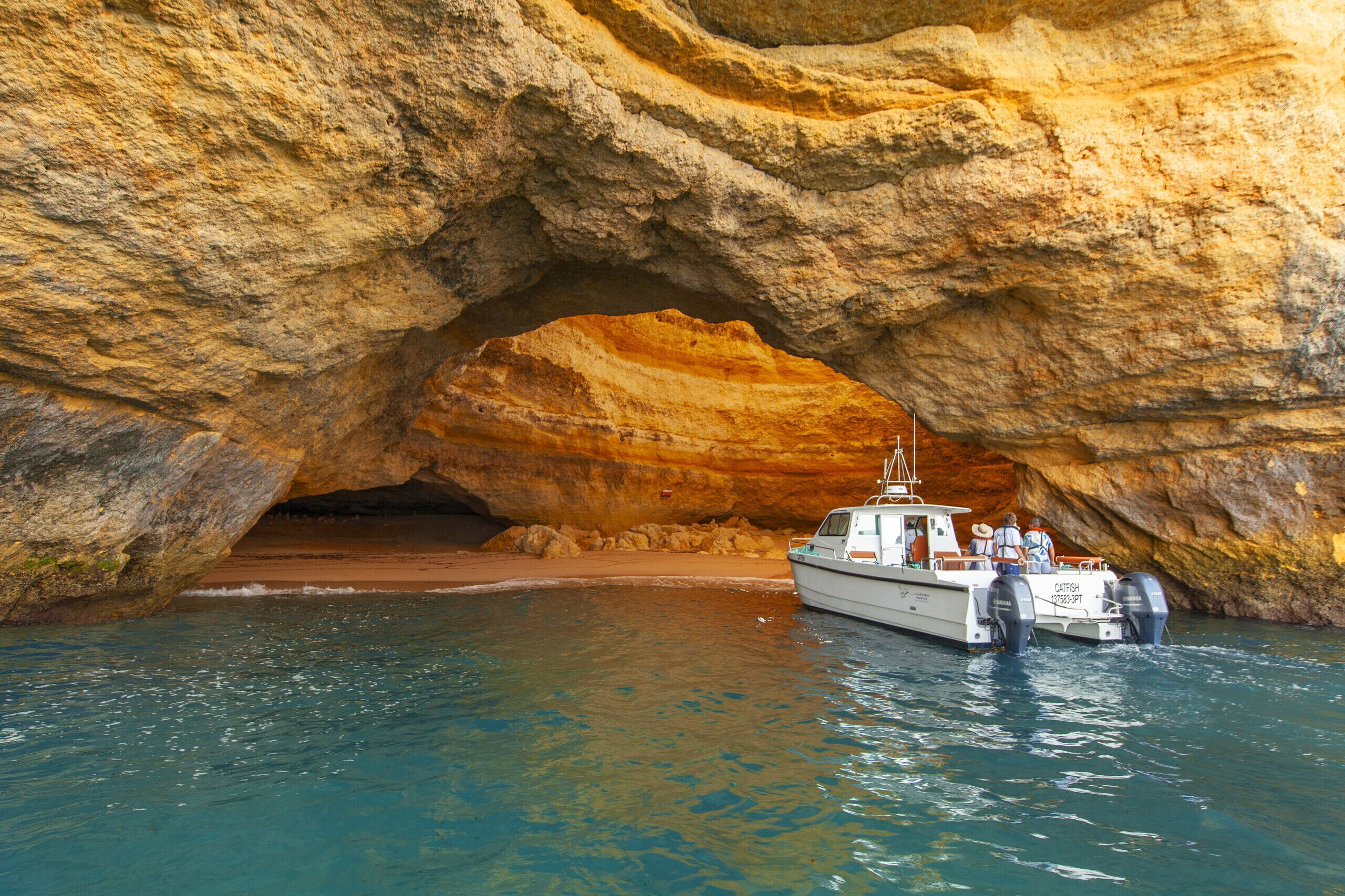 A boat docked at a natural rock formation with a cave-like entrance.