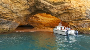 A boat docked at a natural rock formation with a cave-like entrance.