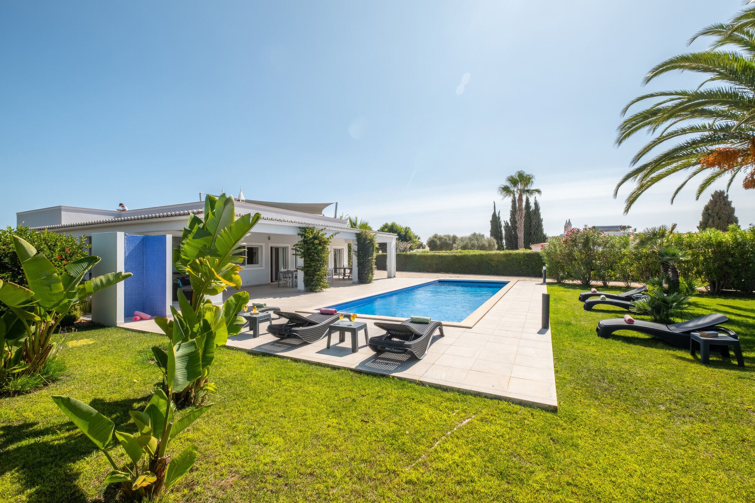 A modern house with a swimming pool, outdoor furniture, and well-maintained lawn.