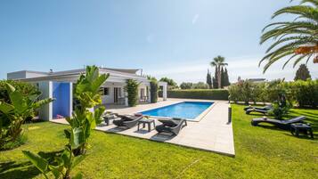 A modern house with a swimming pool, outdoor furniture, and well-maintained lawn.