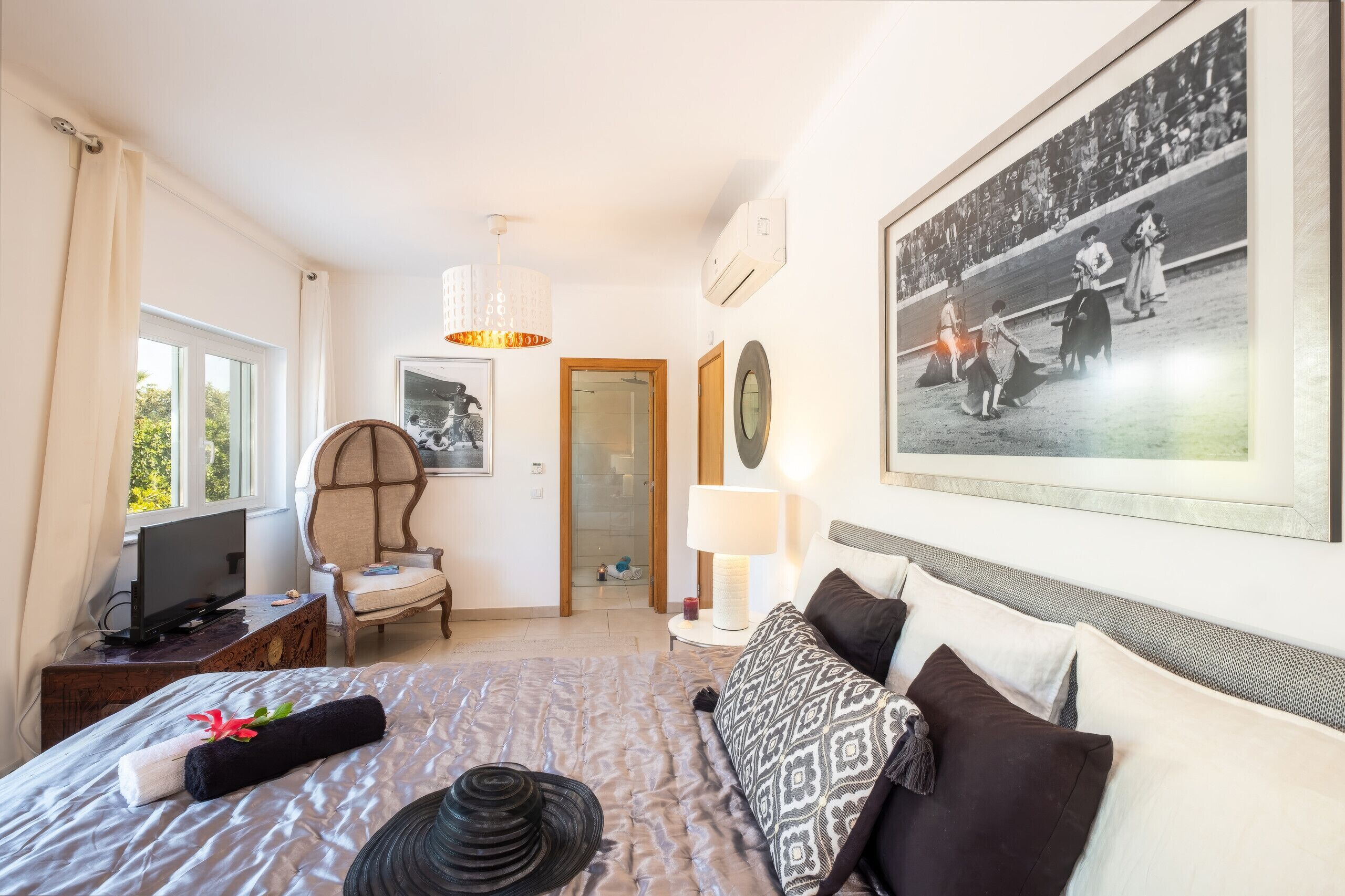 A hotel room with a bed, a chair, a television, a picture on the wall, and a window.