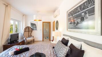 A hotel room with a bed, a chair, a television, a picture on the wall, and a window.