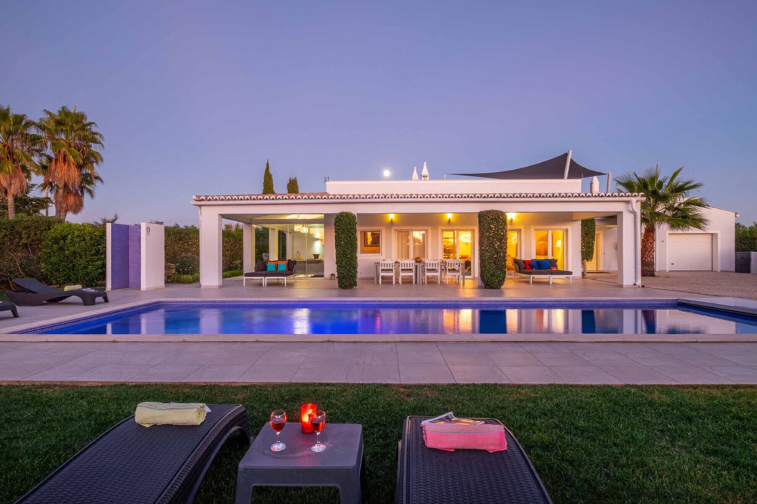 A modern house with a swimming pool, outdoor seating, and a well-maintained lawn.