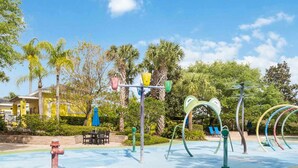 A playground with colorful equipment, a blue pool, and a building in the background. - Top Floor Bahama Bay Condo | 3BR/2BA | 2 Balconies | Near Disney (Davenport)