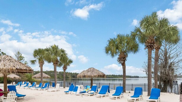 A beach with lounge chairs, palm trees, and thatched umbrellas. - Top Floor Bahama Bay Condo | 3BR/2BA | 2 Balconies | Near Disney (Davenport)