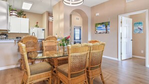 A dining area with wicker chairs, a glass table, and a hanging light fixture. - Top Floor Bahama Bay Condo | 3BR/2BA | 2 Balconies | Near Disney (Davenport)