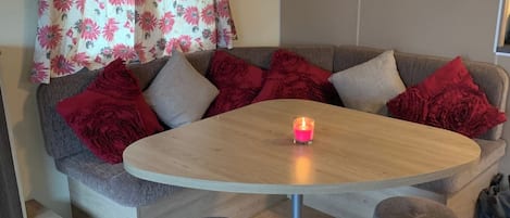 A cozy seating area with a round table, two stools, and a lit candle.